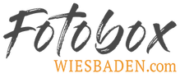Das Logo der Firma Fotobox Wiesbaden. Der Schriftzug "Fotobox" ist in einem stilisierten dunkelgrauen Design, darunter der Slogan "Wiesbaden" in Orange.
