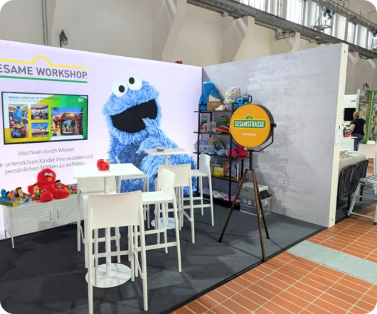 Ein ansprechender Messestand der Sesamstraße, auf dem eine Fotobox mit dem Krümelmonster steht.